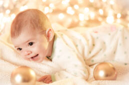 Photograph of baby on blanket with lights in background and bulbs
